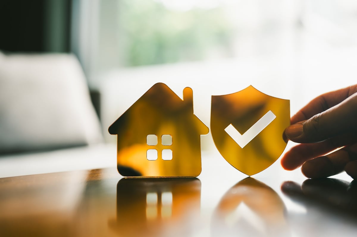 Golden shield with checkmark and house icon symbolizing home insurance