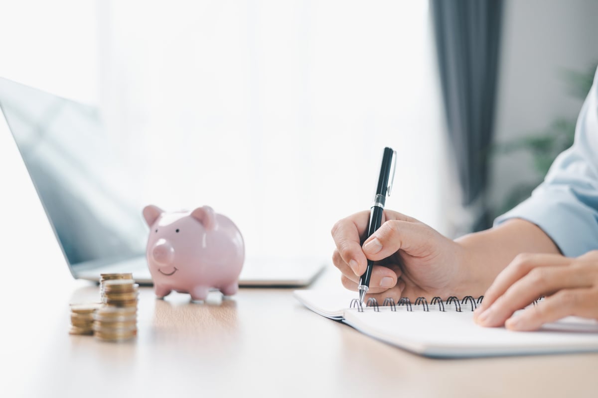Pink piggy bank surrounded by coins on office desk
