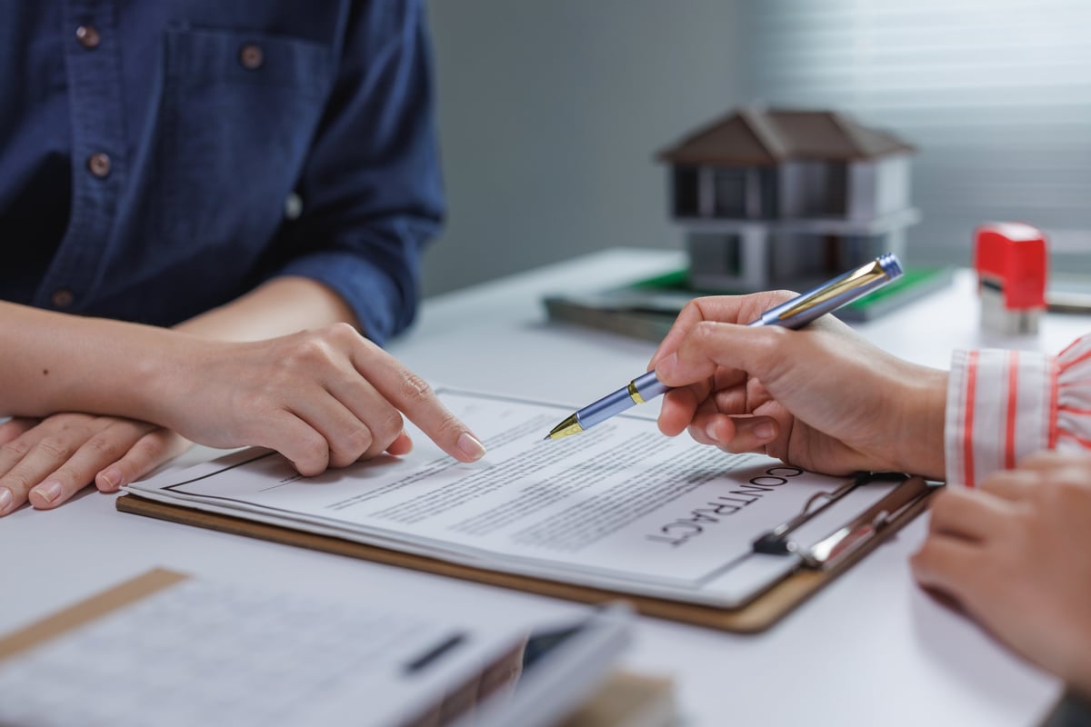 People's hands discussing and signing a contract for a home purchase